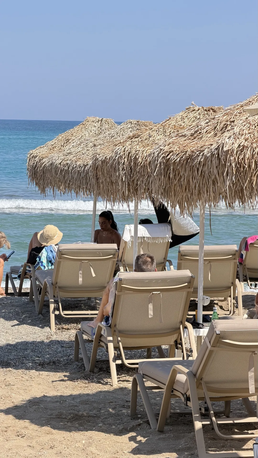 Sun loungers under straw umbrellas facing the sea