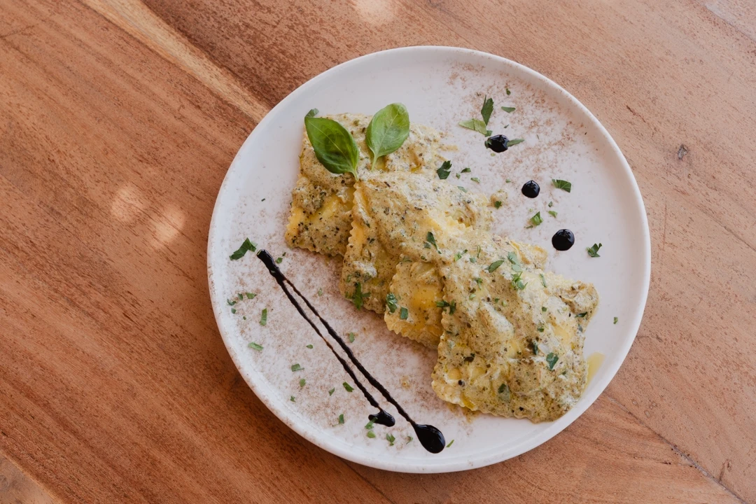 Ravioli plated with herbs and a balsamic drizzle