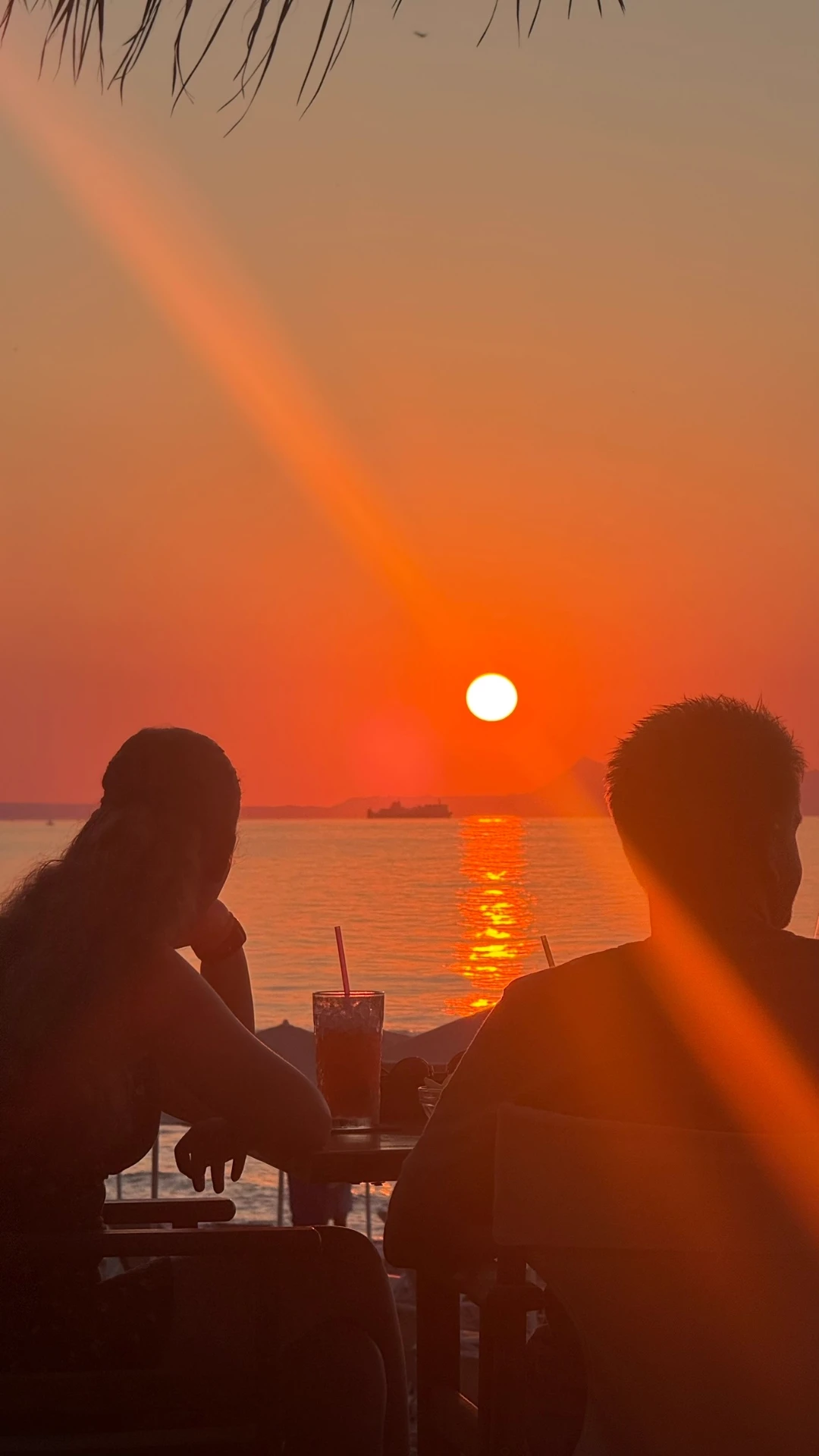 Drinks on the table with warm sun flare over the sea in the background